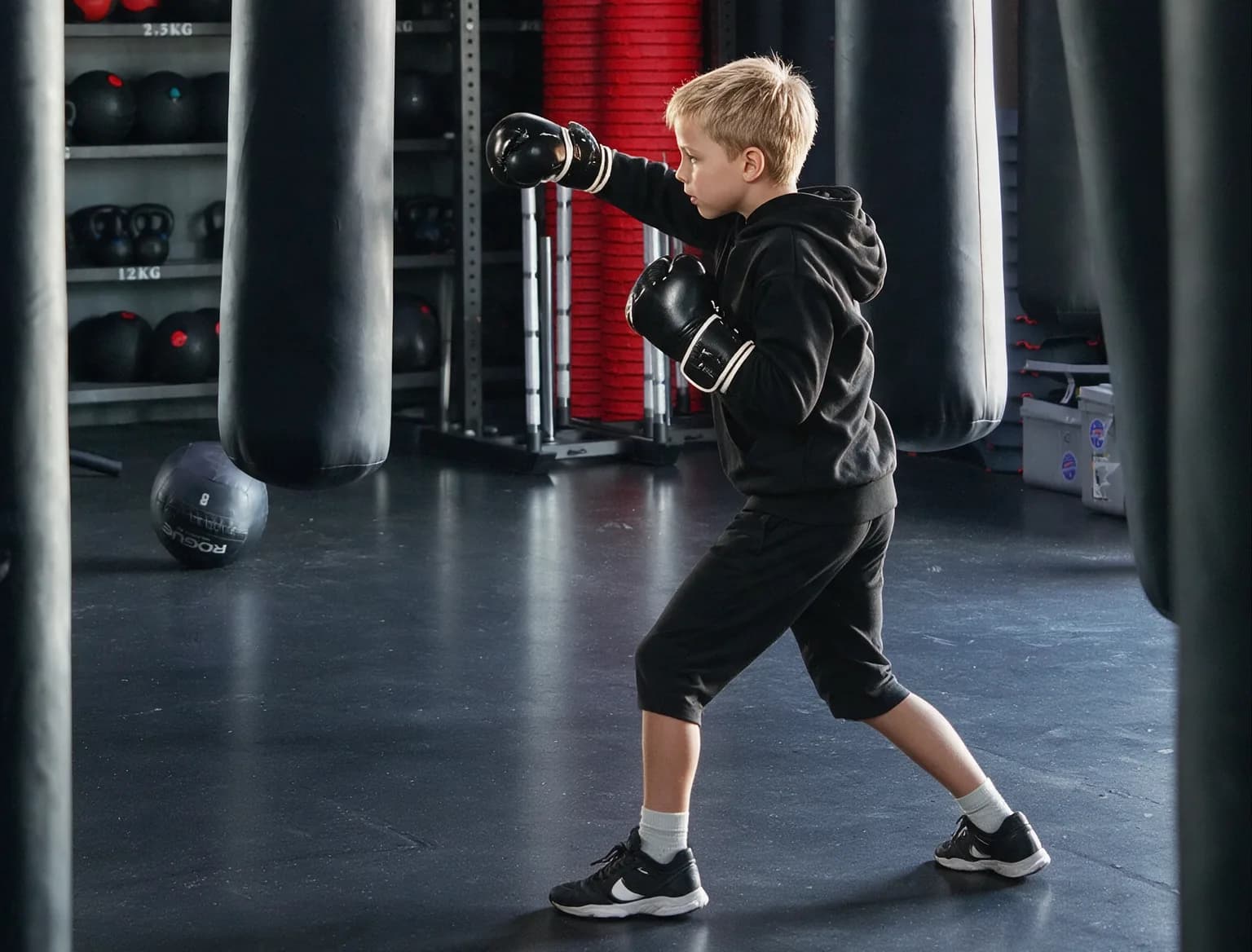 Jeune boxeur en garde, gants noirs, dans la salle de boxe